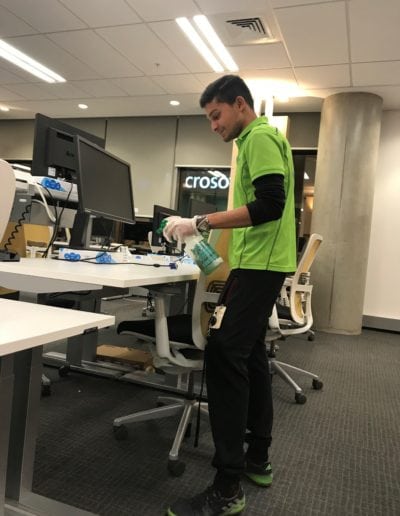 Professional janitor disinfecting office desks for a clean and hygienic workspace