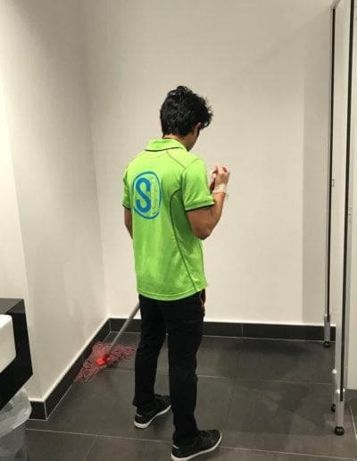 Professional janitor cleaning a restroom floor with a mop